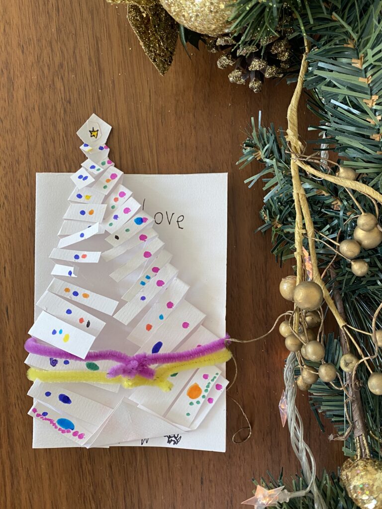 Handmade Christmas tree craft attached to a a handmade card with colorful pipe cleaners.