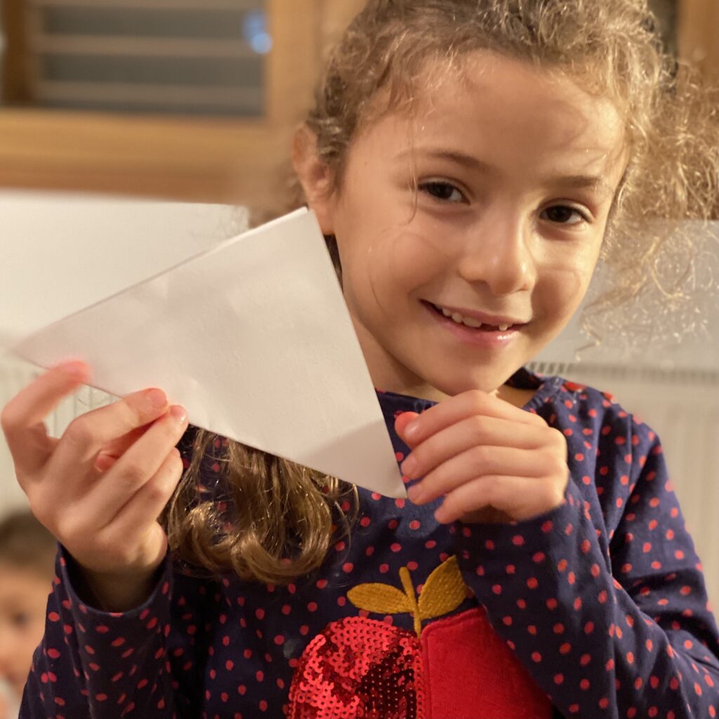 Zoe Panay holding up a folded square piece of paper.